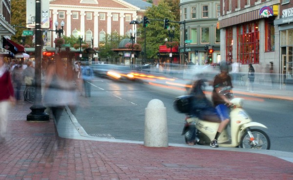 cars and people passing by a busy street